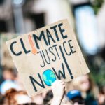 people gathered outside buildings holding Climate Justice Now signage